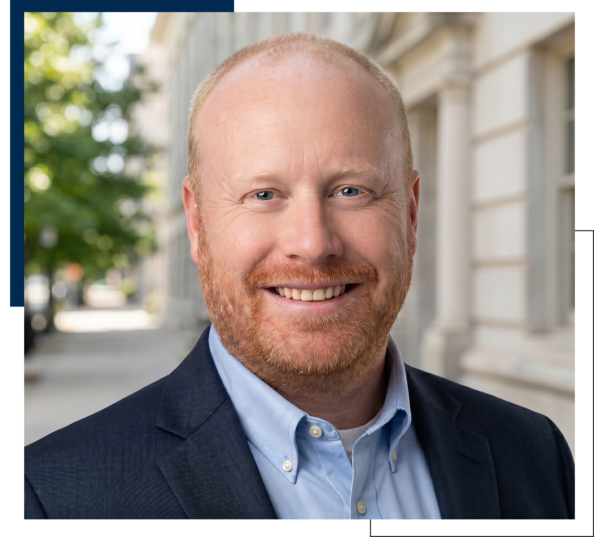 Smiling red-bearded man in suit outdoors